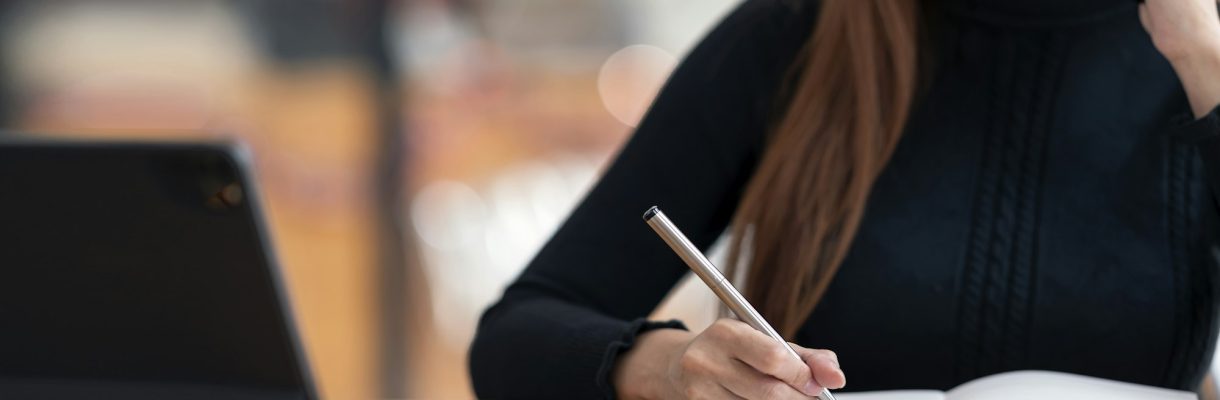 Woman using smartphone, writing note and working on portable tablet